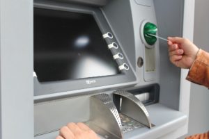 Image: Closeup of an ATM as a hand inserts a card into the reader