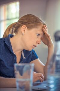 frustrated woman on computer at a counter with water glasses